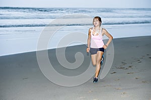 Young attractive and fit Asian sport runner woman running on beach sea side looking tired while hard workout in fitness concept