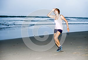 Young attractive and fit Asian sport runner woman running on beach sea side looking tired while hard workout in fitness concept