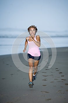 Young attractive and fit Asian sport runner woman running on beach sea side smiling happy in fitness