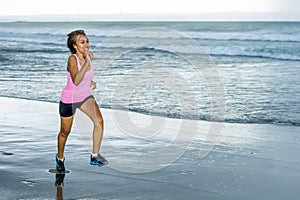 Young attractive and fit Asian sport runner woman running on beach sea side smiling happy in fitness