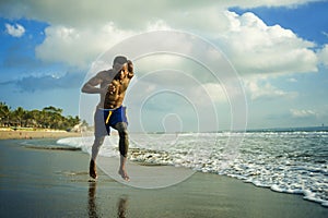 Young attractive fit athletic and strong black African American man running at the beach training hard and sprinting on sea water