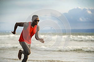 Young attractive fit athletic and strong black African American man running at the beach training hard and sprinting on sea water