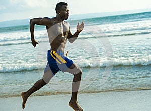 Young attractive fit athletic and strong black African American man running at the beach training hard and sprinting on sea water