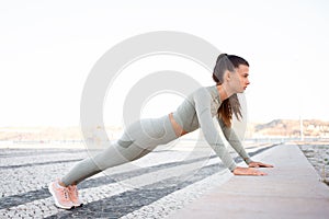 Young attractive girl athlete in sportswear performing push-ups on concrete step