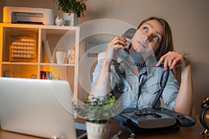 The young attractive girl with dreamy face talking on phone in office at her workplace. Just a regular day at work