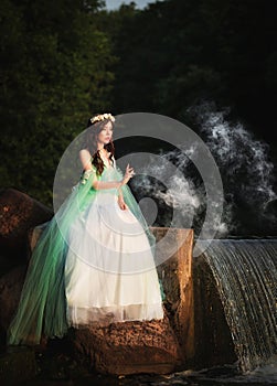 Young attractive girl dressed as fairy in evening garden