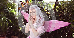 Young attractive girl dressed as fairy in green garden