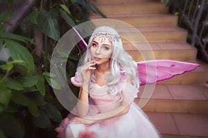 Young attractive girl dressed as fairy in green garden