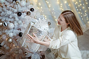 young attractive girl with a gift near the Christmas tree
