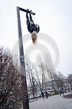 Young attractive Girl hanging by feet upside down on the street light in the street. super extreem. concept of courage