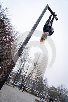 Young attractive Girl hanging by feet upside down on the street light in the street. super extreem. concept of courage