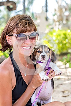 Young attractive girl with her pet dog Beagle at the beach of tropical island Bali, Indonesia. Happy moments.