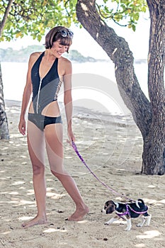Young attractive girl with her pet dog Beagle at the beach of tropical island Bali, Indonesia. Happy moments.