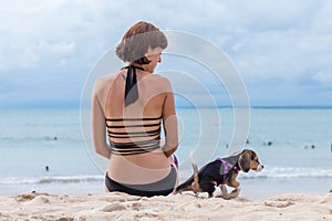 Young attractive girl with her pet dog Beagle at the beach of tropical island Bali, Indonesia. Happy moments.