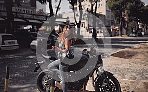 Young attractive girl with the motorbike enjoys the weather