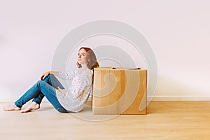 Young attractive girl moving in the new apartment with boxes.