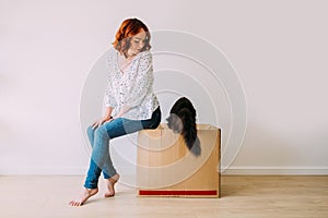 Young attractive girl moving in the new apartment with her cat.