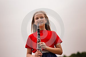 Young attractive girl playing clarinet, ebony in fall park