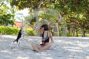 Young attractive girl playing with her pet dog Beagle at the beach of tropical island Bali, Indonesia. Happy moments.