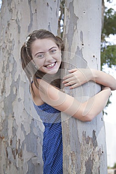 A young attractive girl playing hide and seek in the woods