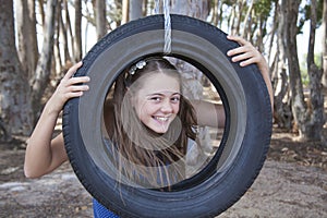 A young attractive girl playing with a tyre swing