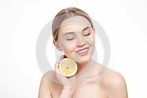 Young attractive girl posing at studio with lemon. Beautiful female face with healthy skin and eyes. Young blonde natural woman