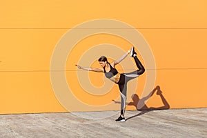 Young attractive girl practicing yoga, standing in natarajasana exercise, holding balance, working out, wearing black sportswear