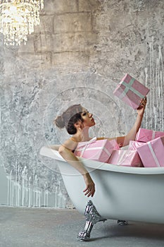 Girl sitting in the bath with gifts