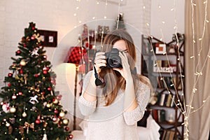 Young attractive girl smiling with dimples and holding cameraphotographer on a background Christmas tree