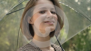 Young attractive girl is spining umbrella in park in daytime, in summer, watching at camera, flirt concept