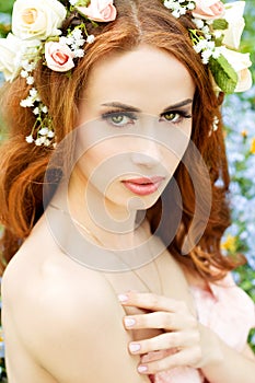 Young attractive girl on a sunny day of flowering with flowers in red hair