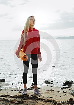 Young Attractive Girl With A Yoga Mat After Practice Relaxation. Biohacking Fitness Sport Health By The sea