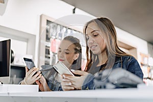 Young attractive girls in electronics store buy phone. concept of buying gadgets