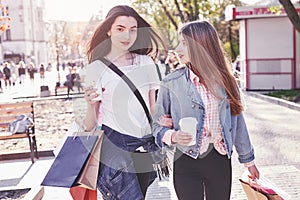 Young attractive girls with shopping bags and coffee in the city