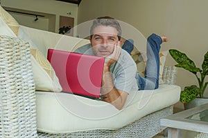 Young attractive and handsome happy man lying at home sofa couch working with laptop computer netbook relaxed in internet business