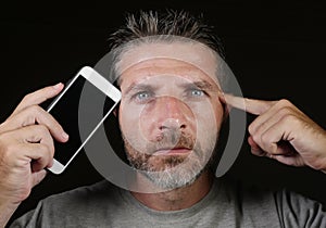 Young attractive and handsome internet addict man holding mobile phone against his face in social media app and online dating