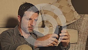 Young attractive and handsome man sitting at living room floor focused and concentrated using mobile phone networking or dating