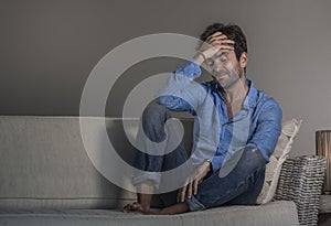 Young attractive and handsome sad latin man sitting tired and depressed at home sofa couch feeling overwhelmed and worried sufferi