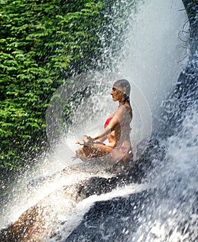 Young attractive and happy 30s woman with fit body practicing yoga wet under tropical paradise waterfall stream in meditation and