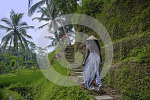 Young attractive happy afro american black woman 30s exploring rice fields forest and jungle in Bali wearing asian hat