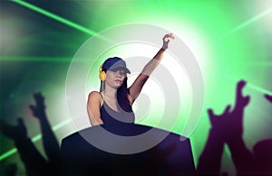 Young attractive and happy Asian Chinese DJ woman remixing using deejay gear and headphones at night club with lights background