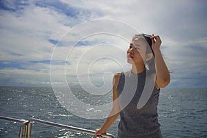 Young attractive and happy Asian Chinese woman on excursion ship or ferry enjoying sea breeze on summer holiday sea boat trip