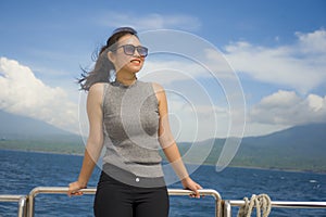 Young attractive and happy Asian Chinese woman on excursion ship or ferry enjoying sea breeze on summer holiday sea boat trip