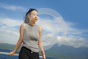 Young attractive and happy Asian Chinese woman on excursion ship or ferry enjoying sea breeze on summer holiday sea boat trip