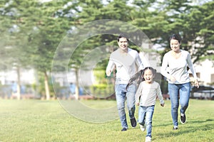 Young attractive happy asian family playing by running together in outside nature park in home school learning or montessori