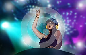 Young attractive and happy Asian Japanese DJ woman remixing using deejay gear and headphones at night club with lights background