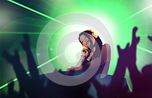 Young attractive and happy Asian Japanese DJ woman remixing using deejay gear and headphones at night club with lights background