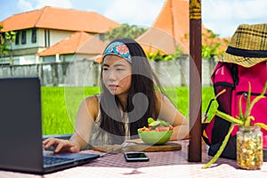 Young attractive and happy Asian Korean digital nomad working outdoors relaxed with laptop computer at tropical cafe in success on