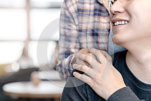 Young attractive happy asian man and woman holding hands on shoulder looking and talking together with love and care at cafe with