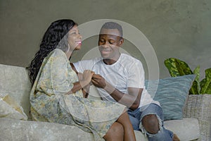 Young attractive and happy black African American couple relaxed at home sofa couch talking sweet enjoying together and smiling in